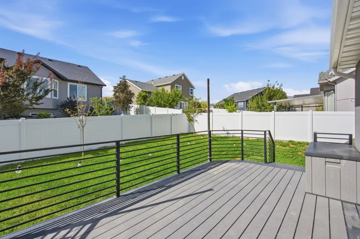 Composite decking with black metal railings, leading to a vibrant green lawn