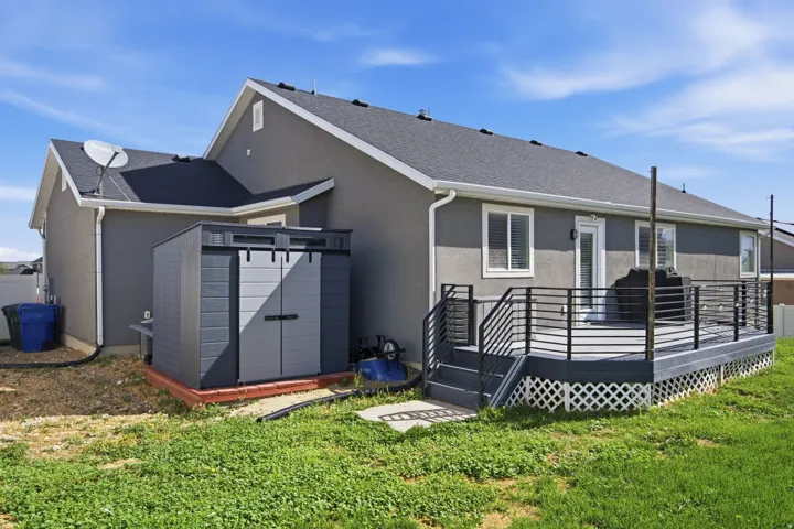 Rear exterior with a spacious elevated deck featuring black metal railings and lattice skirting