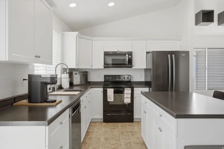 Modern kitchen featuring white cabinetry, dark wood-finish countertops, stainless steel appliances, and recessed lighting