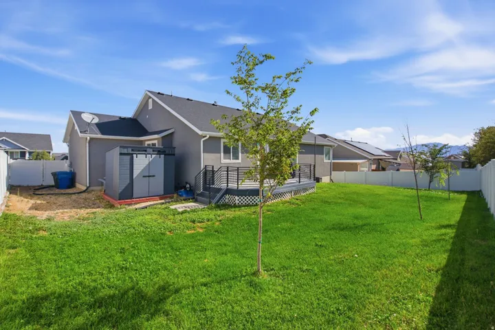 Spacious backyard featuring a built-in storage shed, a multi-level deck with black railings, and a white privacy fence
