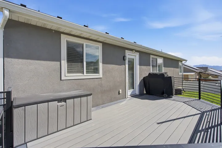 Exterior deck with composite decking, black metal railings, and a white framed glass door