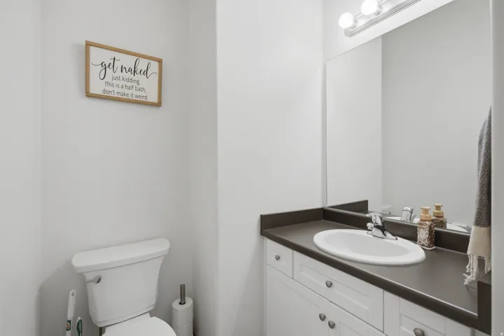 White vanity with shaker-style door and drawer fronts, integrated oval sink, and dark countertop