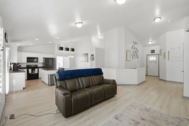 Vaulted ceilings throughout, wood-finish flooring, recessed lighting, white cabinetry, and stainless steel appliances