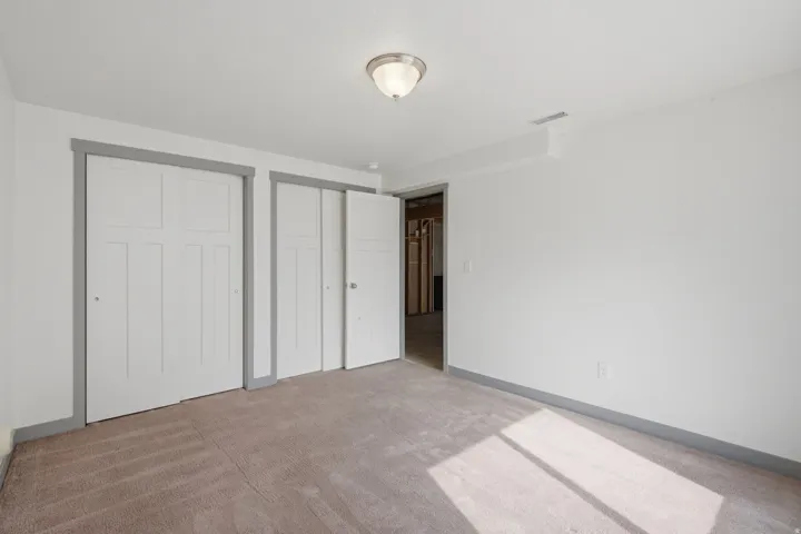 Neutral-toned carpeting, white walls, two bi-fold closet doors, and recessed ceiling lighting