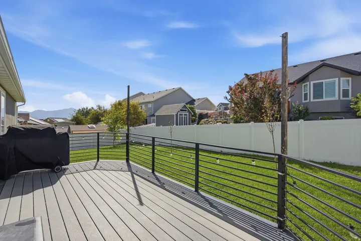 Expansive deck featuring composite decking and black horizontal railings, overlooking a green lawn with a white privacy fence