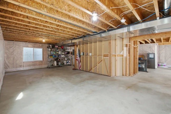Unfinished basement featuring exposed wood joists, concrete flooring, and framed walls