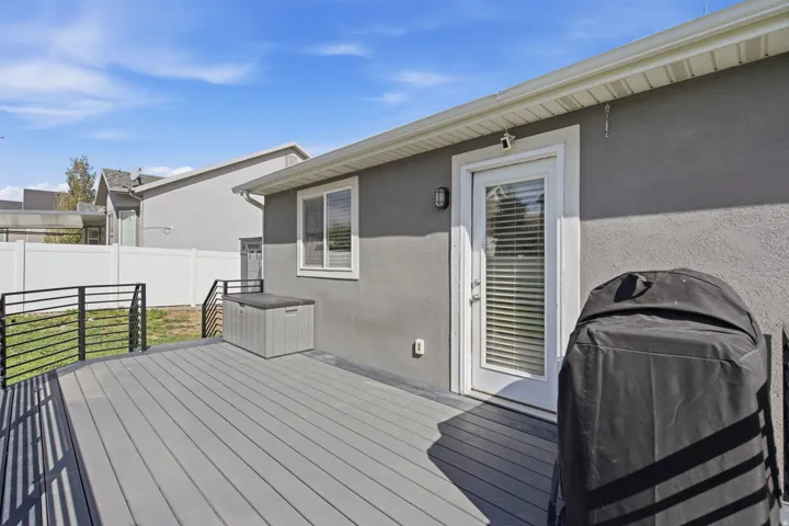 Composite deck with integrated black metal railings, leading to a white privacy fence