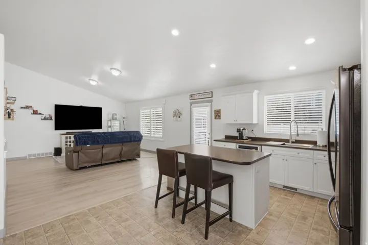 Kitchen featuring white cabinetry, a kitchen island with seating, a stainless steel sink, and durable tile flooring