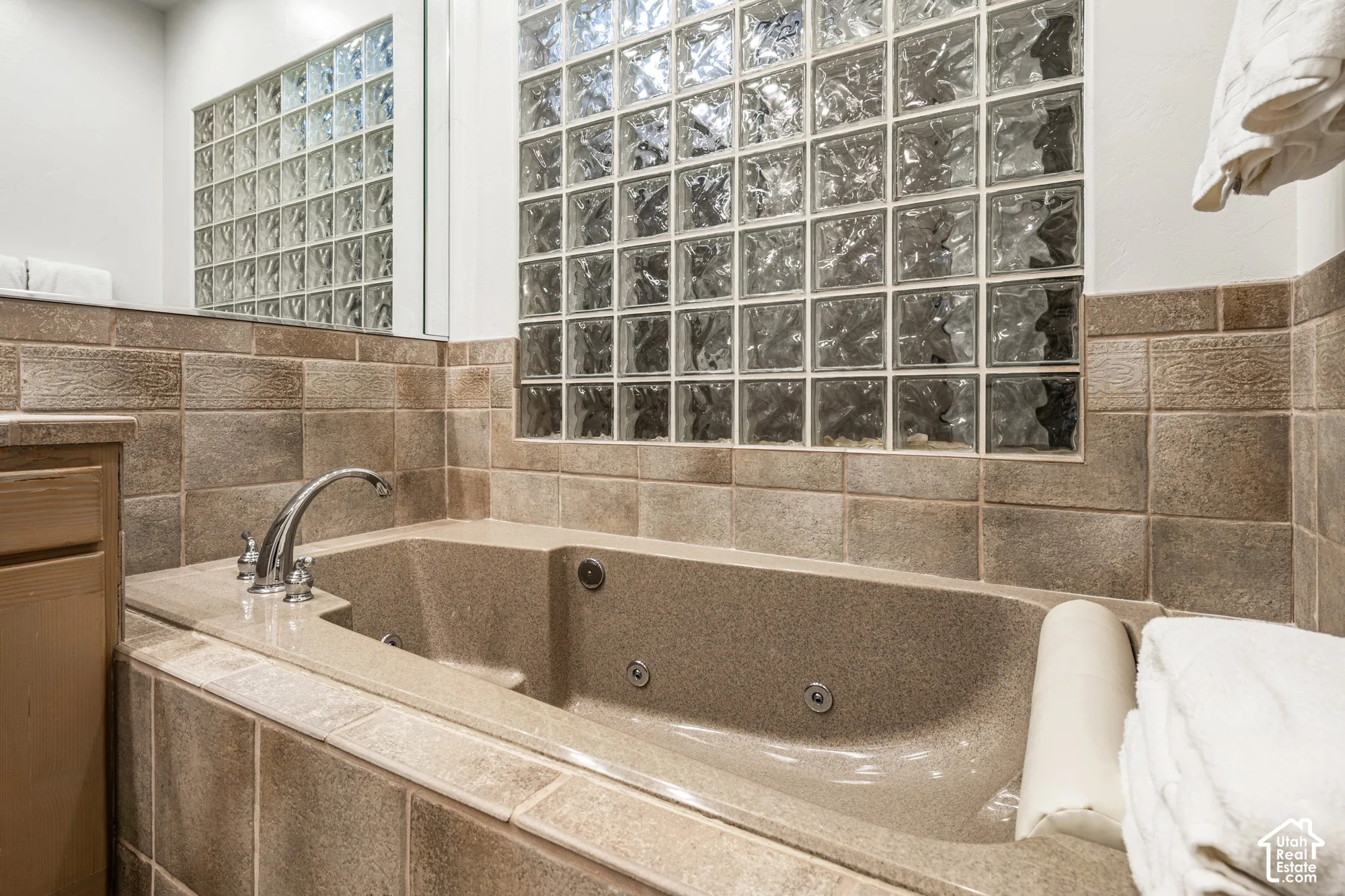 Soaking tub with jetted features, chrome fixtures, and surrounding tilework