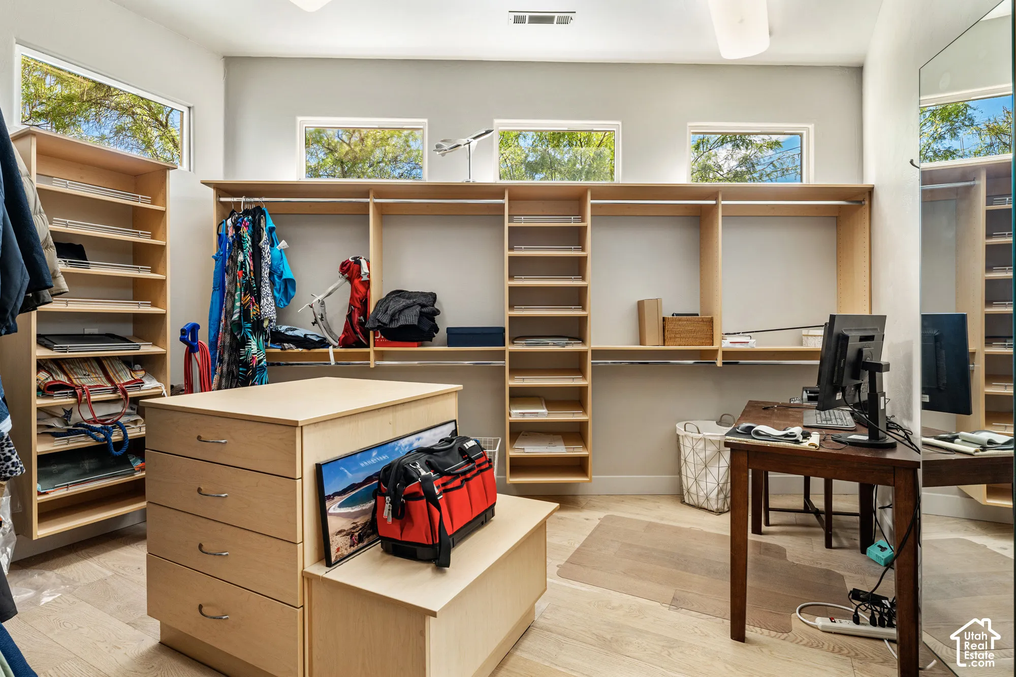 Built-in wood-finish shelving and hanging storage with a central drawer island