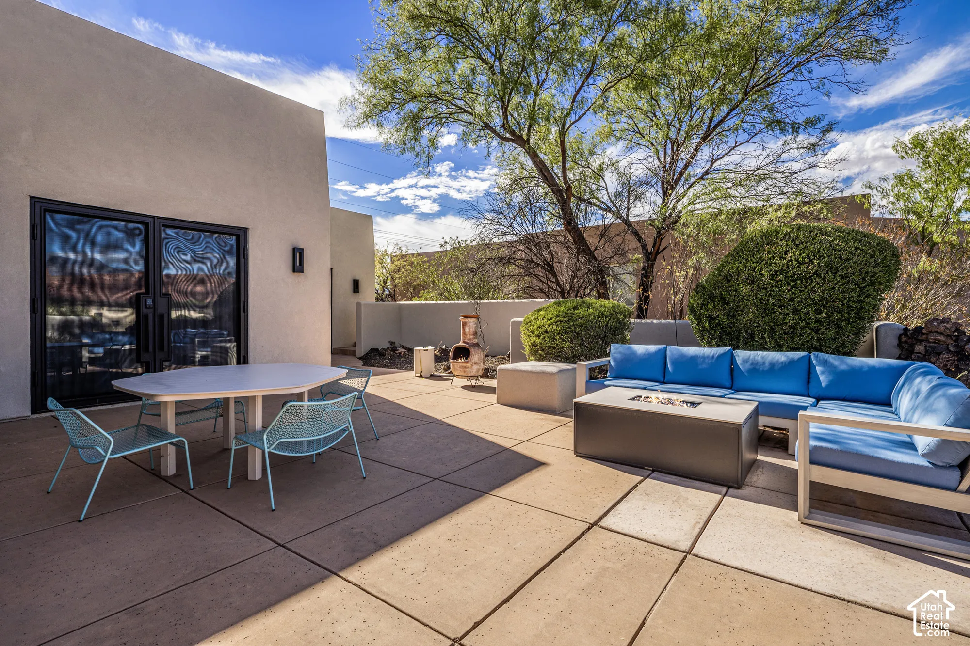 Expansive outdoor patio with concrete pavers, stucco exterior, and mature landscaping