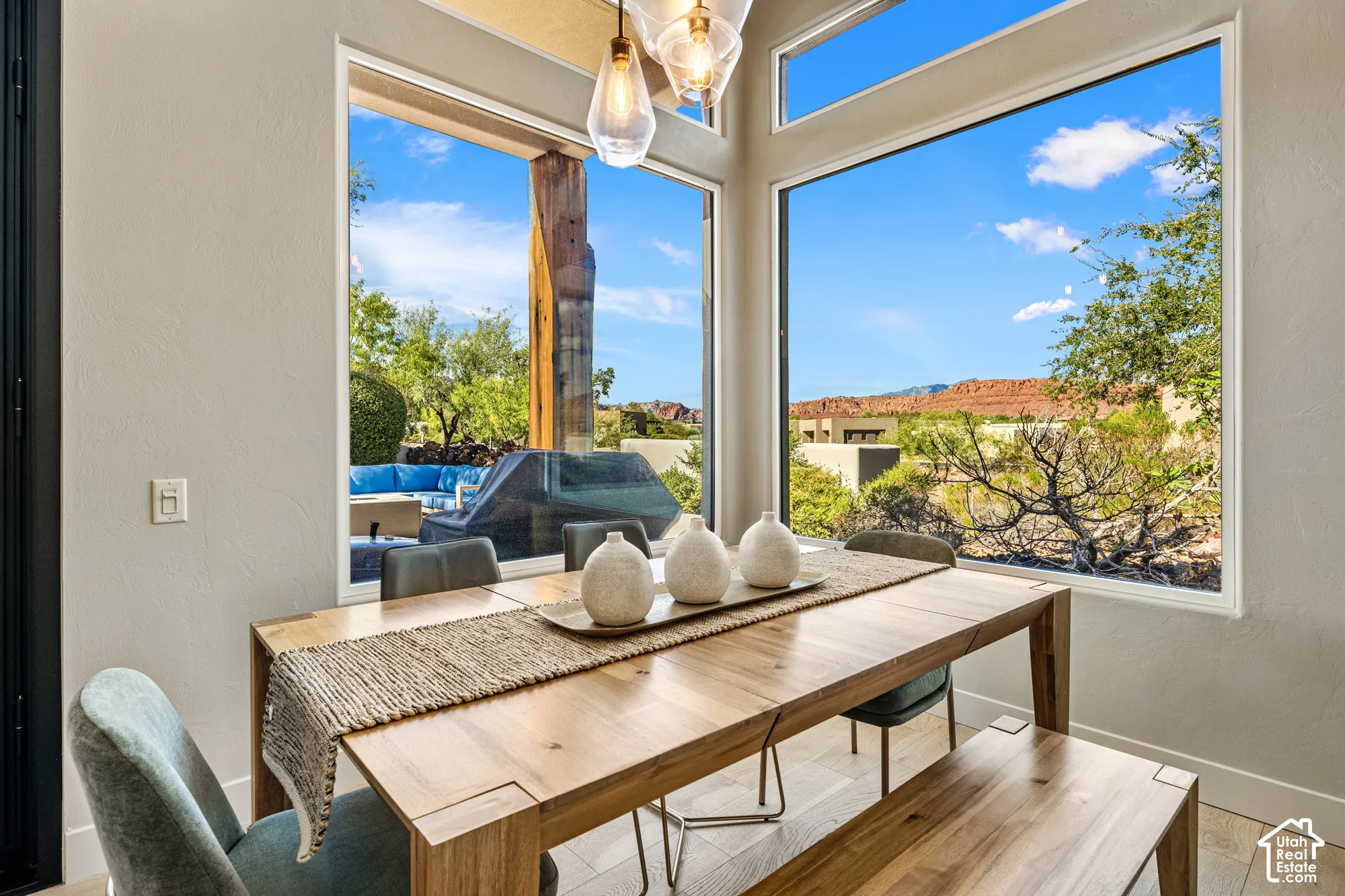 Expansive windows showcasing mountain scenery, a patio with built-in seating, and a wood-finish dining table with integrated bench seating