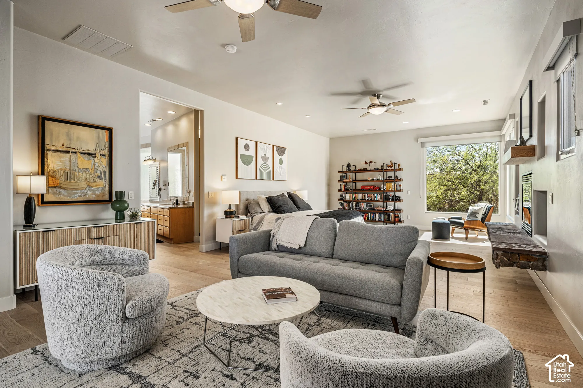 Wood-finish flooring, recessed lighting, and ceiling fans complement the large window and built-in shelving