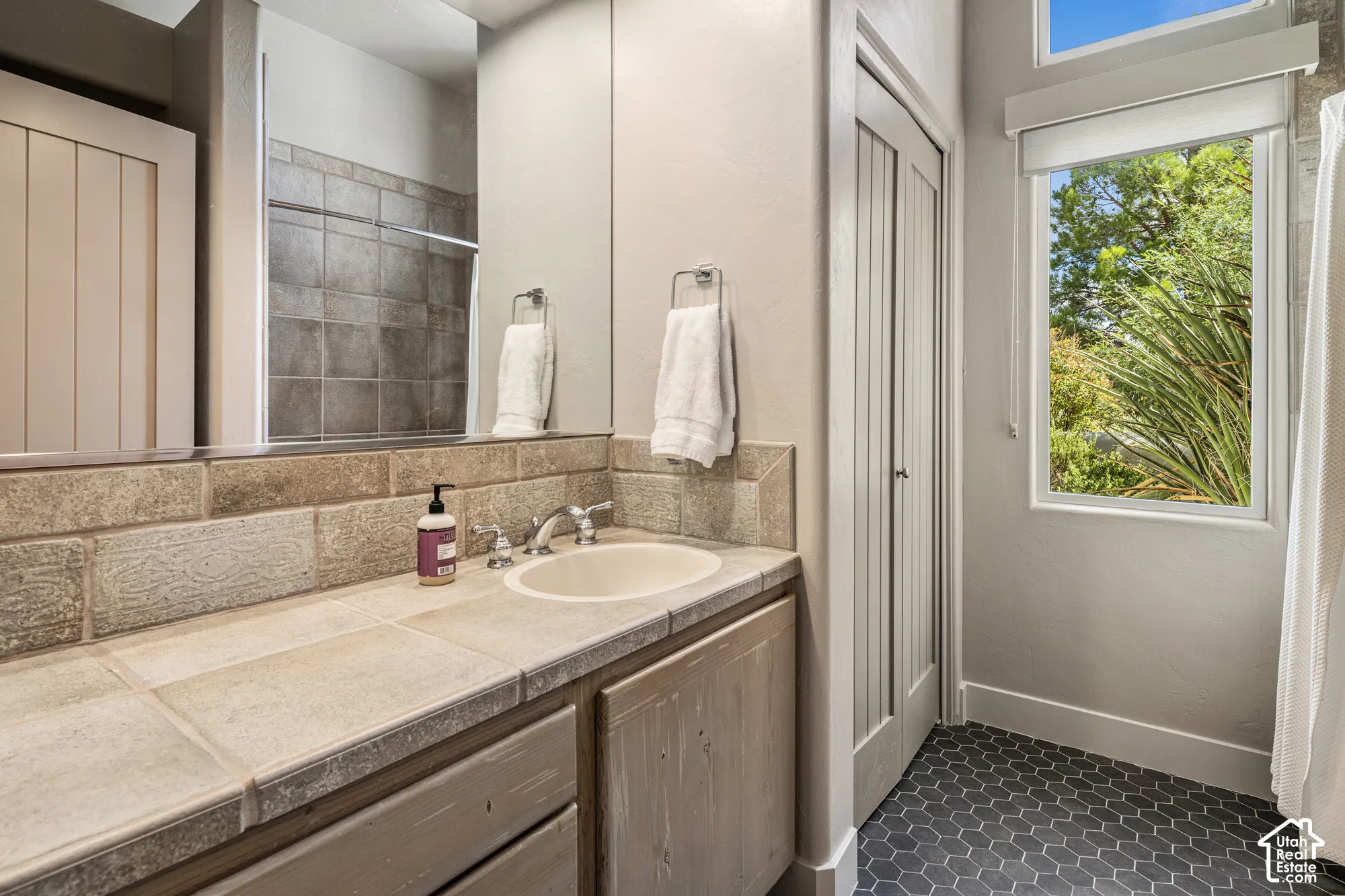 Vanity with tile countertop, integrated sink, and wood-finish cabinetry