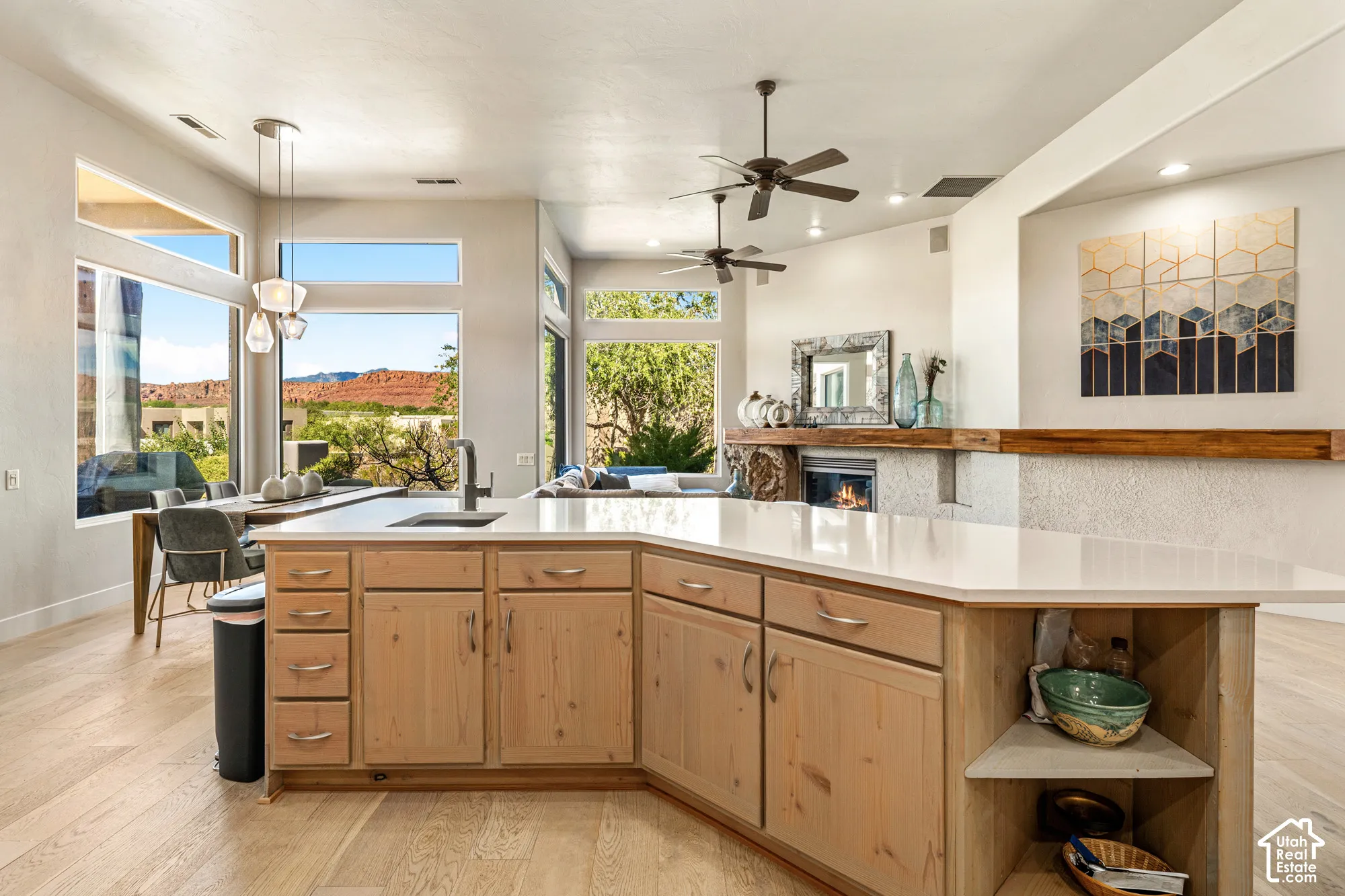 Open-concept kitchen with light wood cabinetry, white countertops, and wood-finish flooring