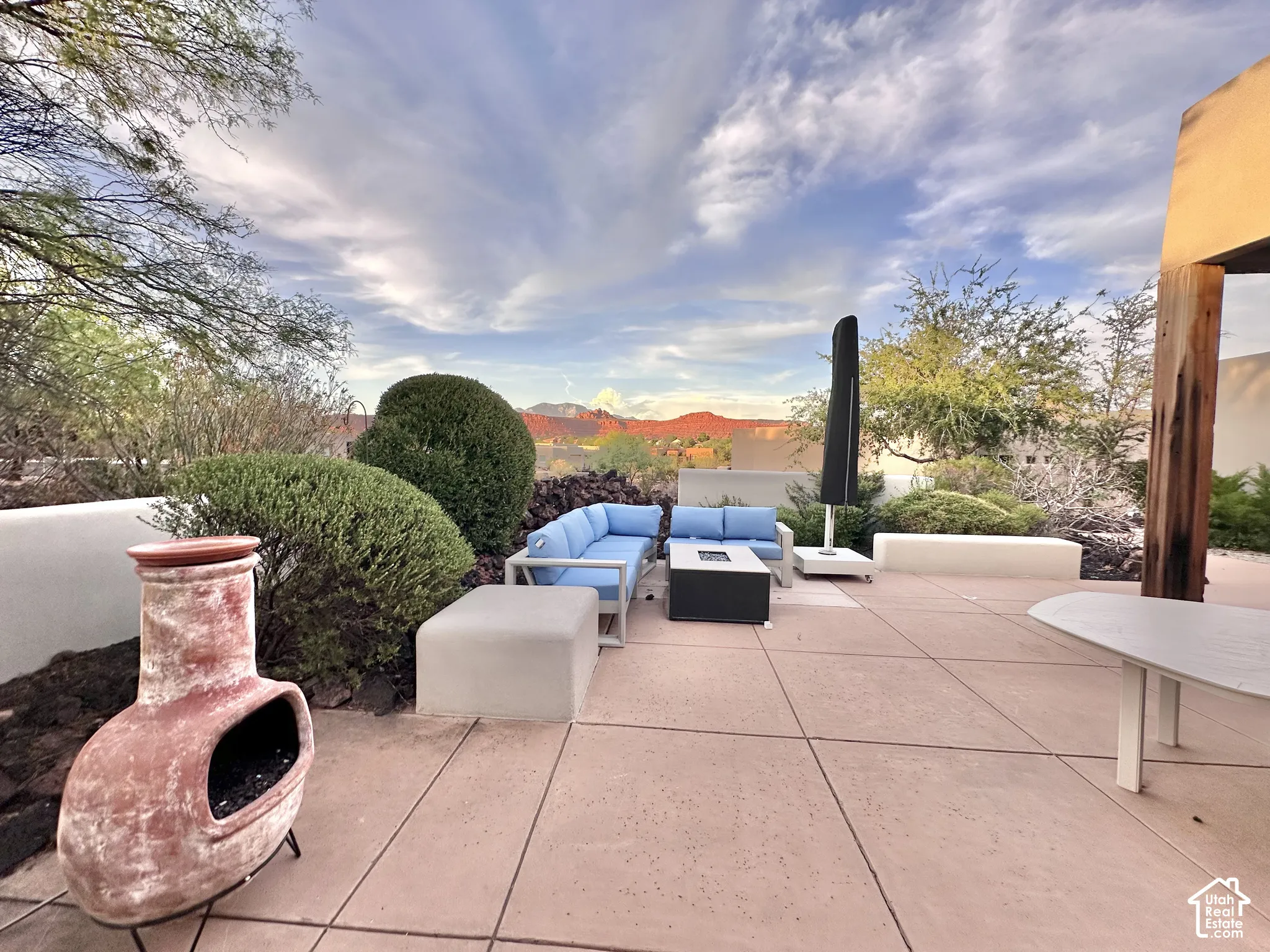 Expansive outdoor patio featuring concrete paving, low stucco walls, and desert landscaping