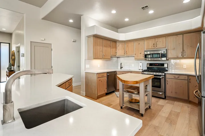 Spacious kitchen featuring light wood-finish cabinetry, stainless steel appliances, white subway tile backsplash, and light-toned countertops