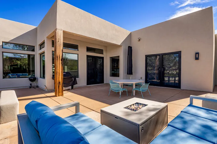 Expansive concrete patio with a modern fire pit, large multi-pane windows, and black frame French doors