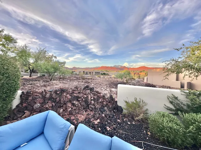 Expansive outdoor area with a natural rock retaining wall and desert landscaping