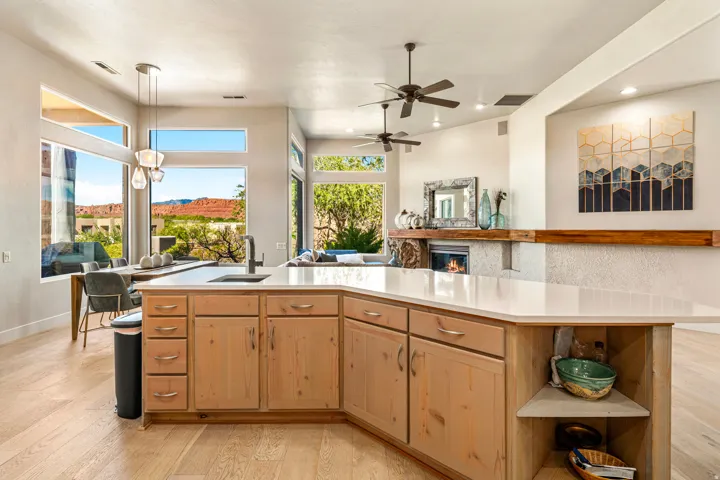 Open-concept kitchen with light wood cabinetry, white countertops, and wood-finish flooring