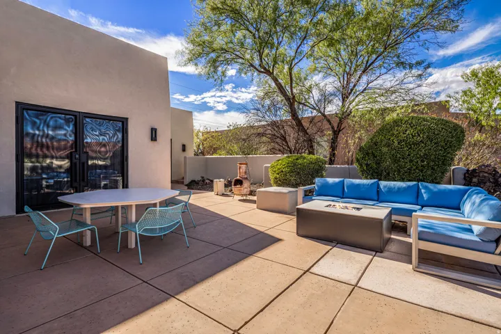 Expansive outdoor patio with concrete pavers, stucco exterior, and mature landscaping