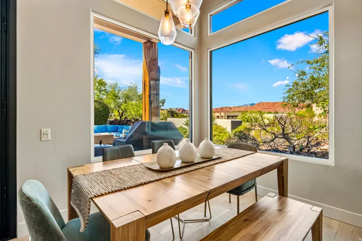 Expansive windows showcasing mountain scenery, a patio with built-in seating, and a wood-finish dining table with integrated bench seating