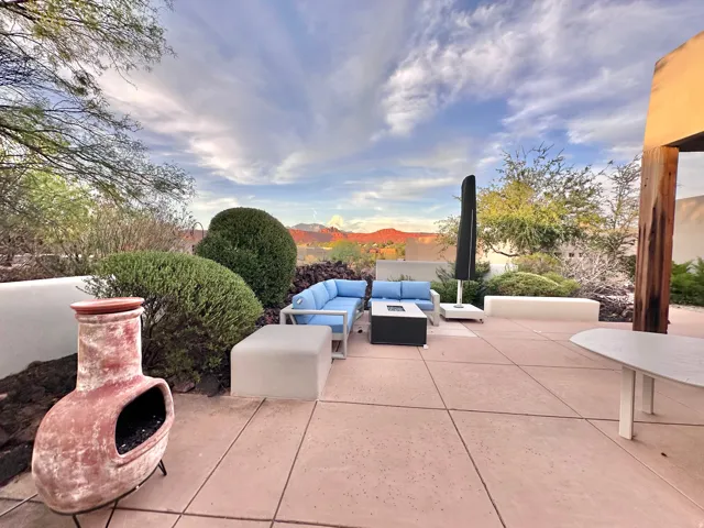 Expansive outdoor patio featuring concrete paving, low stucco walls, and desert landscaping