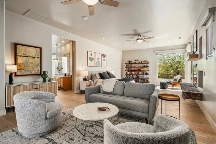 Wood-finish flooring, recessed lighting, and ceiling fans complement the large window and built-in shelving