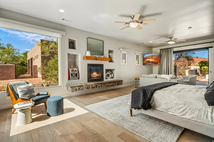 Integrated living space with wood-finish flooring, a built-in fireplace with a stone hearth, and recessed wall niches
