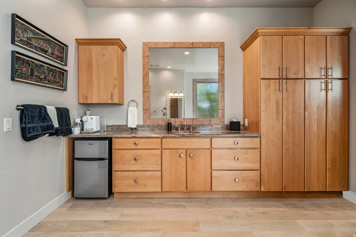Spacious vanity with light wood cabinetry, stone-finish countertop, and ample storage