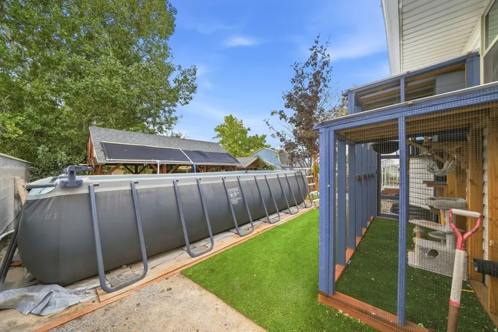 Backyard space featuring an above-ground swimming pool, artificial turf, and a screened enclosure