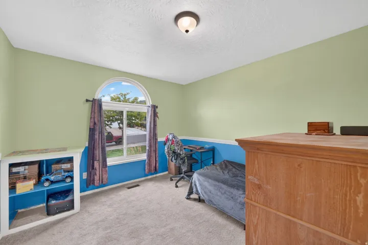 Arched window with white trim, built-in shelving, carpet flooring, and a flush mount ceiling light