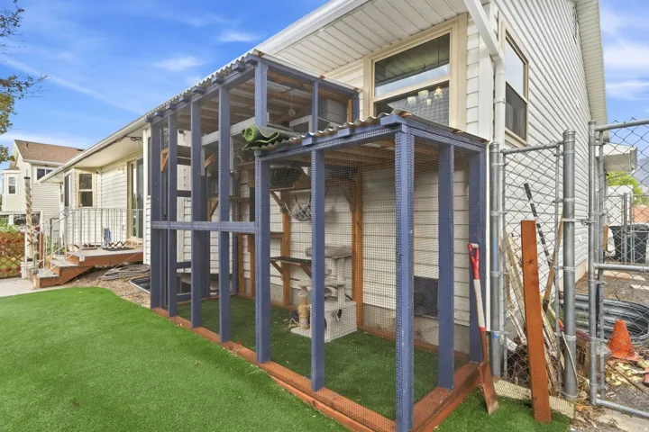 Expansive turf yard featuring a multi-level outdoor enclosure with wood framing and a corrugated roof