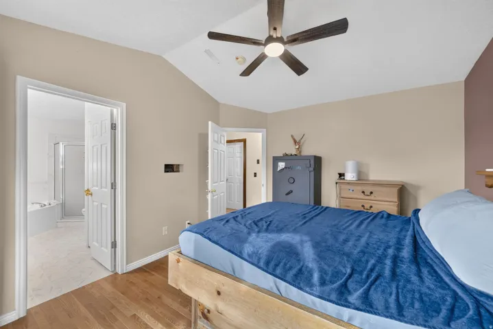 Vaulted ceiling with ceiling fan, wood-finish flooring, and white paneled doors