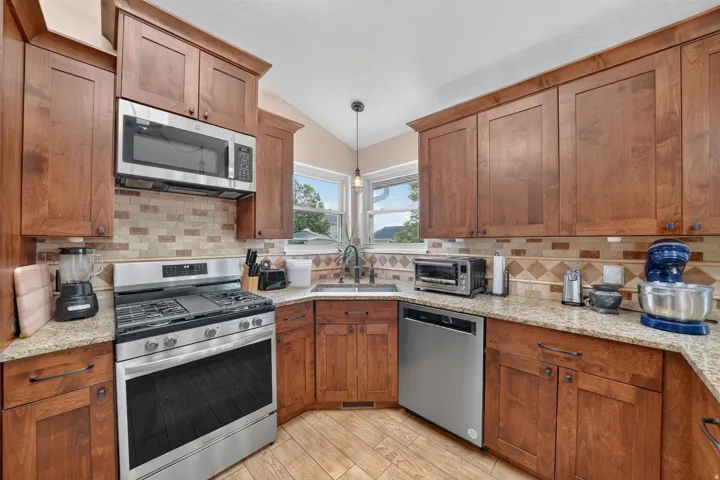 Wood-finish cabinetry paired with light-toned countertops and a mosaic tile backsplash