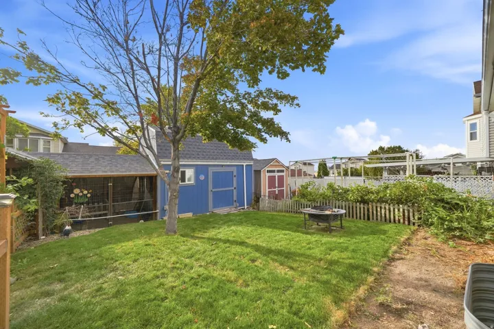 Manicured lawn with a blue shed, small brown shed, and wooden privacy fencing