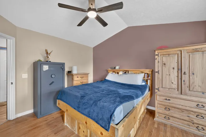 Vaulted ceiling with a ceiling fan, light wood-finish flooring, and two-tone wall paint