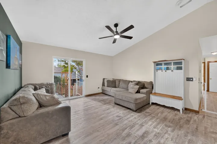 Vaulted ceiling with a ceiling fan, wood-finish flooring, and sliding glass door