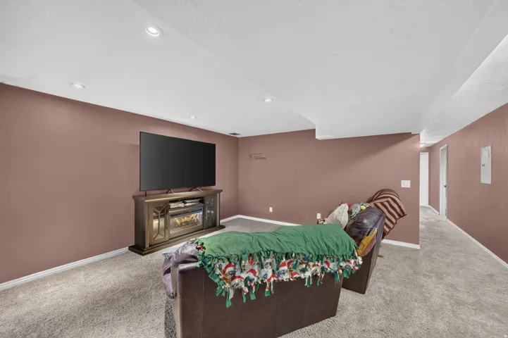 Recessed lighting illuminates a spacious room featuring wall-to-wall carpeting and a decorative electric fireplace