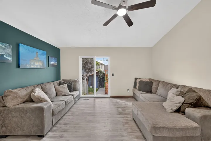Wood-finish flooring, recessed lighting, ceiling fan, sliding glass door, and a contrasting accent wall