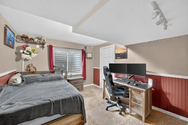 Room featuring textured carpeting, neutral-toned walls, and a lower wall section with vertical paneling