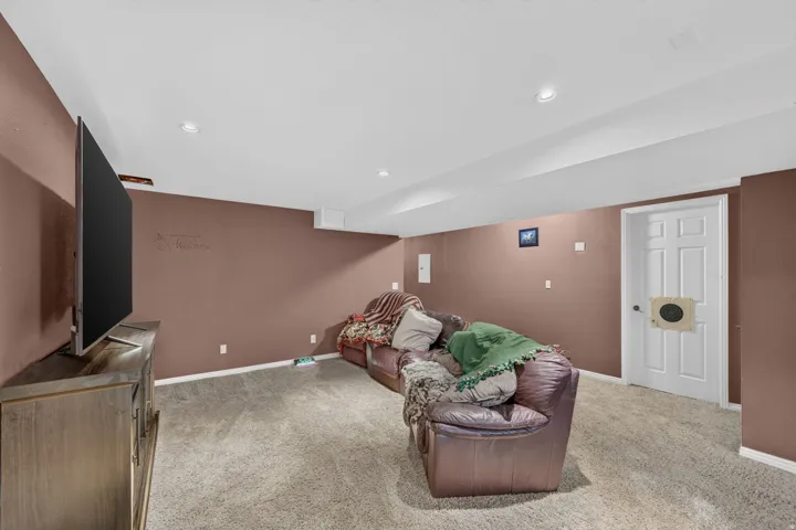 Recessed lighting illuminates this room featuring wall-to-wall carpeting and a paneled door