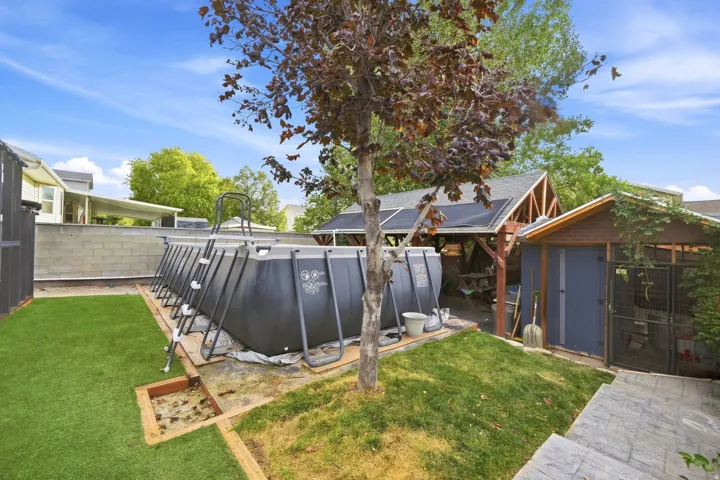 Above-ground pool, artificial turf, wood-frame gazebo, storage shed, and stamped concrete patio