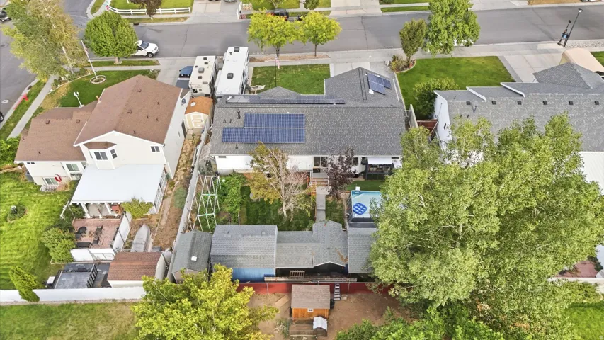 Rear exterior with solar panels, mature trees, and an in-ground pool
