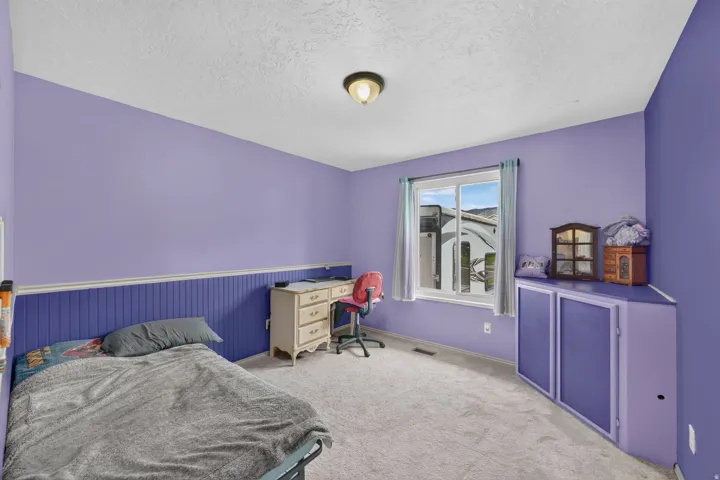 Window with natural light, light-colored carpeting, built-in corner cabinetry, beadboard wall paneling
