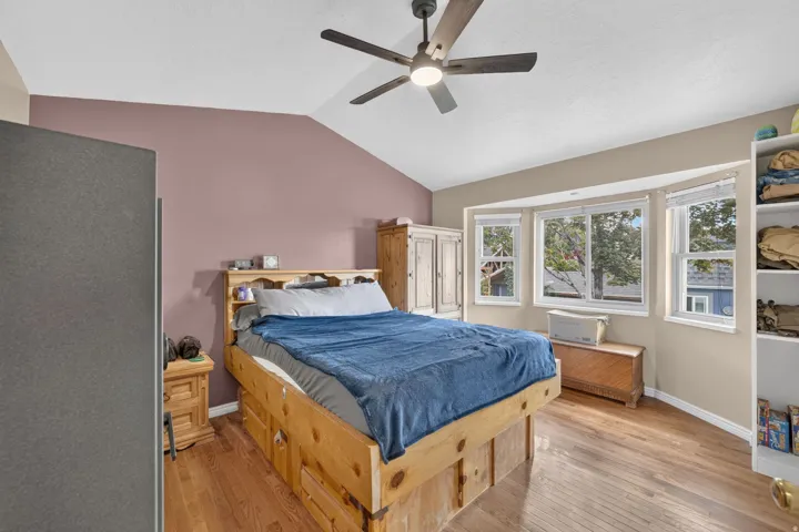 Vaulted ceiling, wood-finish flooring, ceiling fan with integrated lighting, bay window, built-in shelving