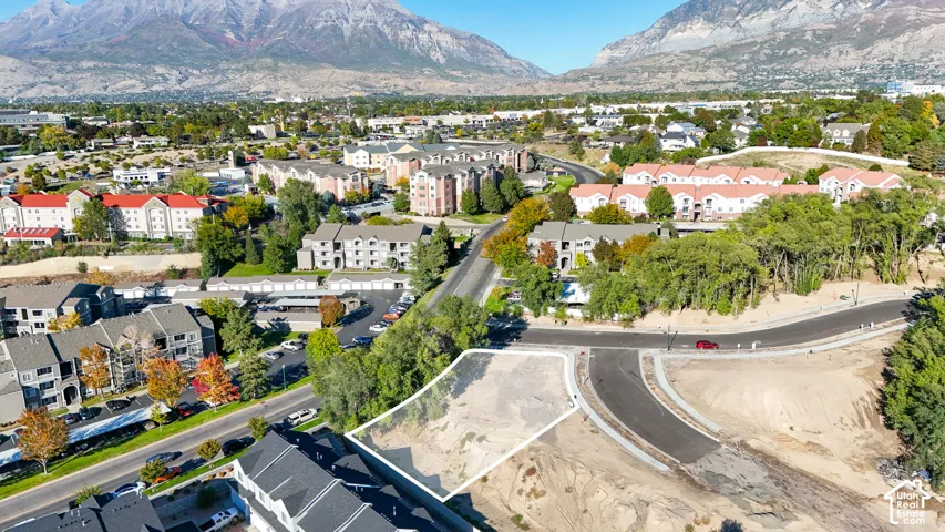 Mountain backdrop, developed residential area, paved roads, established trees, and surrounding multi-story buildings