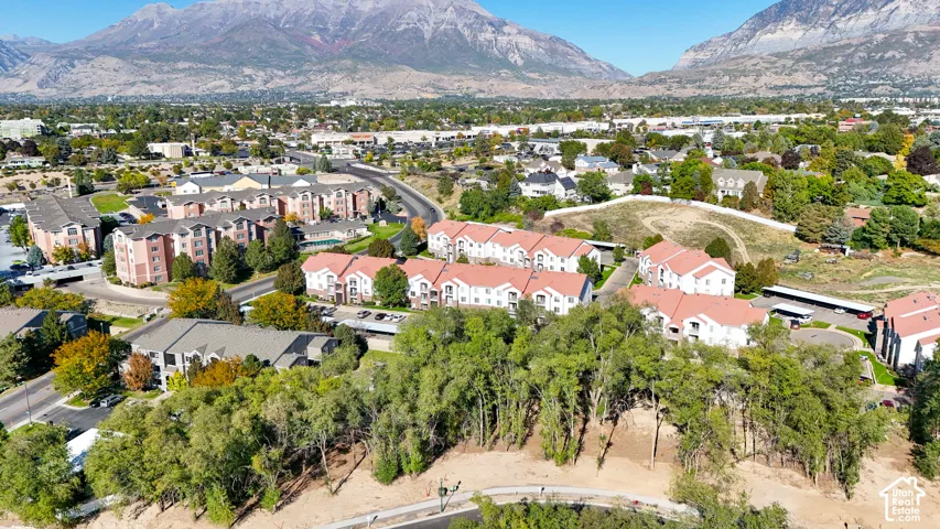 Expansive mountainous backdrop framing a dense residential area with mature trees and multiple buildings featuring red-tiled roofs
