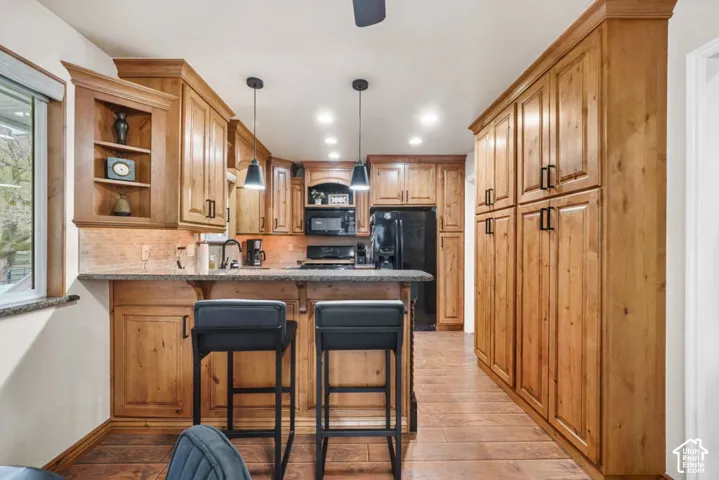Kitchen featuring wood-finish cabinetry, built-in pantry storage, and a breakfast bar with stone-finish countertops