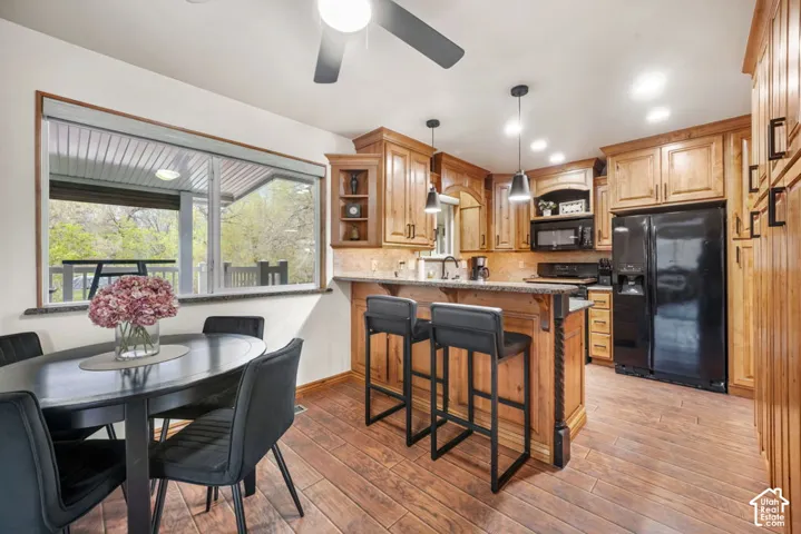 Kitchen featuring wood-finish flooring, natural wood cabinetry, a central island with bar seating, and a large window